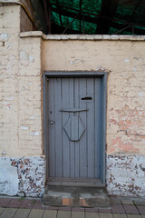 Grey door on old painted rouge worn brick wall 