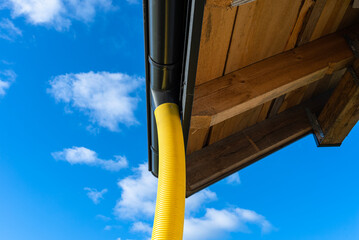 100mm diameter yellow PVC pipe connected to the end of the gutter on the roof, protected against water.