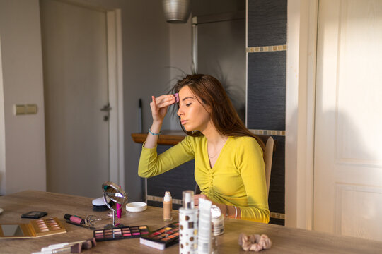 Young teenage woman doing make up in her living room. 