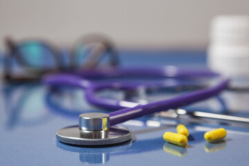 Close-up of a stethoscope and pills reflected on surface's table