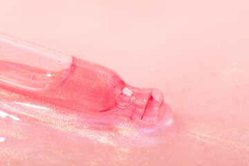 Fototapeta premium A cosmetic pipette lies in a pink liquid. Or rose gold liquid with sparkles. Laboratory research of cosmetics, gel, medicine. Chemistry