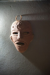 interesting mask on gray wall with light shining on one side