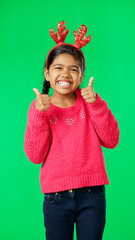 Child portrait, christmas and thumbs up on green screen for motivation or mindset. Smile of girl kid on studio background with antlers headband excited for holiday celebration thank you or like emoji