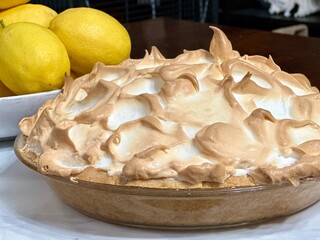 Close up of lemon meringue pie with lemons in the background