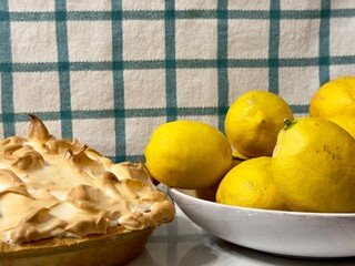 Lemon meringue pie next to a bowl of fresh lemons