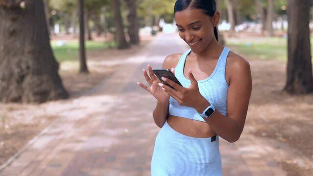 Phone, laughing athlete and woman at park on break with comedy, meme or joke after run. Sports, cellphone and funny Indian person browsing online, social media or comic video after training outdoor