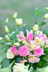 beautiful bouquet with eustoma and roses flowers close up on abstract blurred green background. Gentle romantic floral festive image. template for design. copy space