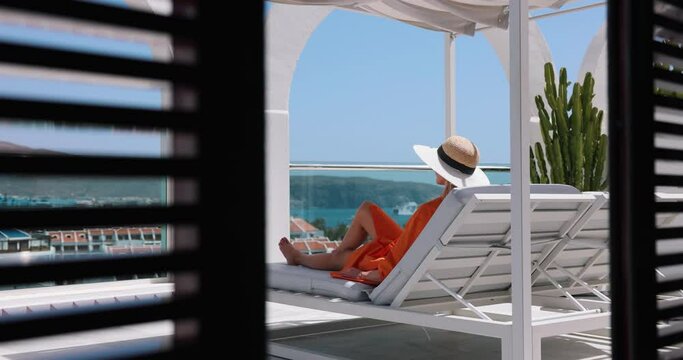 woman relaxing in sunbed and enjoy the summer vacation at luxury rooftop penthouse terrace with sea view. rear view