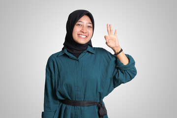 Portrait of excited Asian muslim woman with hijab showing ok hand gesture and smiling looking at camera. Advertising concept. Isolated image on white background
