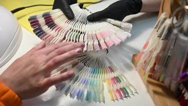 Woman hands holding manicure nail color samples palette. Beauty and health of nails