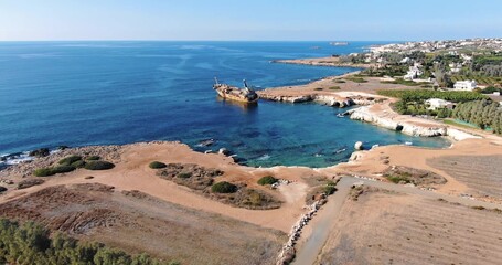 Flying drone over the coastline of the island overlooking an old rusty sunken ship or liner EDRO...