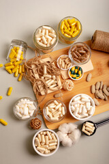 Nutritional supplements, organic minerals and many different vitamins such as vitamin a, d3, c, e, b in small glass jars and plates on wooden desk from above on light background in rustic style. 