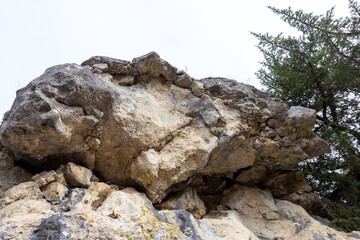 Natural stone walls are the entrance to a cave on a vertical rock of a mountain canyon.