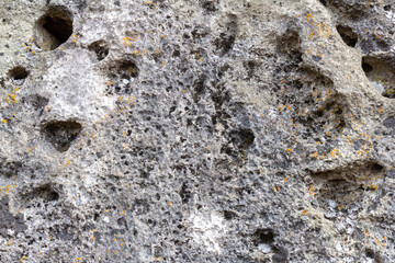 Natural stone walls are the entrance to a cave on a vertical rock of a mountain canyon.