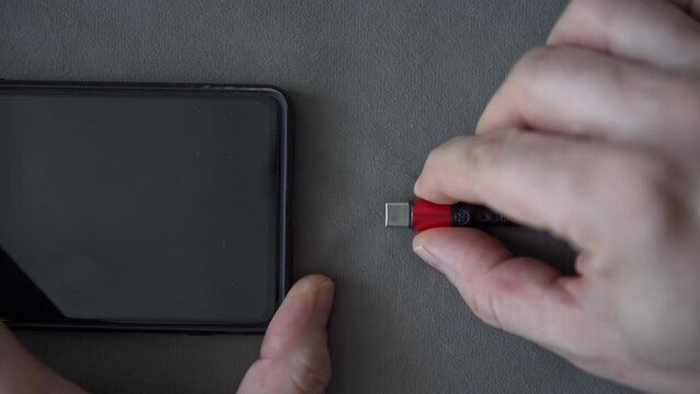 Hands removing micro usb plug from cell phone socket