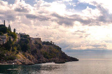 Coast of Antalya harbour with cliff and stones in the sea during a cloudy day