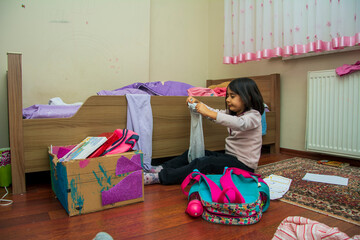 Little girl organizes her things in her messy room
