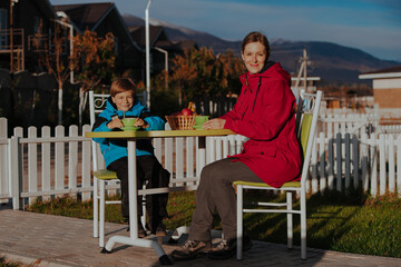 Mother and son drink tea in the yard of a country house