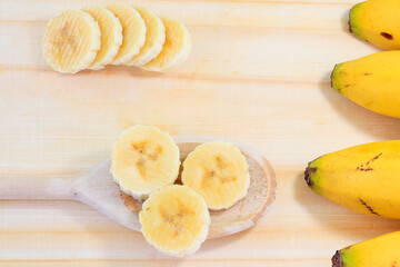 Close up Banana slices on spoon over wooden background. Healthy natural snack