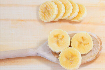 Close up Banana slices on spoon over wooden background. Healthy natural snack