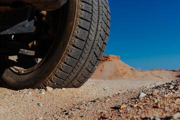 Fototapeta na wymiar Car wheel on sand close-up view