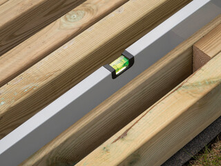 Spirit level or construction water level checking the level of a plank of wood. Close up image.
