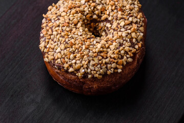 Delicious donut with cream filling and nuts on a dark concrete background