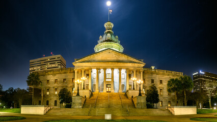 Fototapeta na wymiar Illuminated South Carolina State House, in Columbia, SC, under a starry sky with a full moon. The South Carolina State House is the building housing the government of the U.S. state of South Carolina
