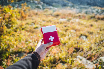The first aid kit lies in the hand against the background of grass, first aid in a bag with a...