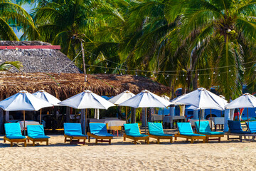 Palms parasols sun loungers beach people Zicatela Puerto Escondido Mexico.