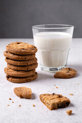 Close-up of baked oatmeal chocolate chip cookies and milk in a glass. Selective focus. Vertical orientation.