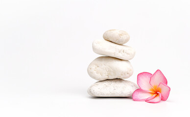 Fototapeta na wymiar white pebbles and frangipani on white background. Stones pyramid. Life balance and harmony concept, spa 