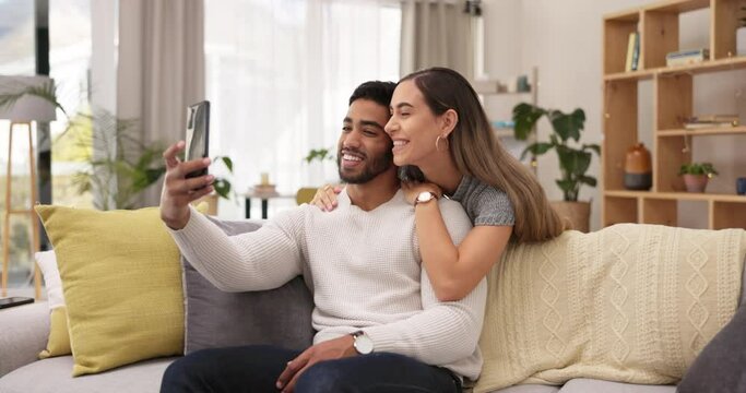 Happy couple, hug and kiss in selfie on sofa for profile picture, vlog or memory relaxing together at home. Man and woman kissing, hugging and smiling for photo, social media or love in living room