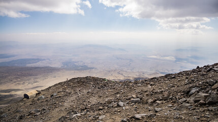 Rocky slope made of stones on Mount Ararat on a sunny summer day with clouds, slopes with scree and tents on the slope
