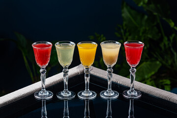 Alcoholic cocktail on a transparent table against a blue background and plants