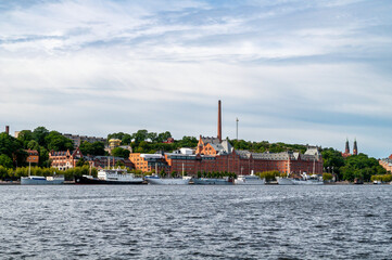 Naklejka premium Stockholm, Sweden - Quay with ships and a large factory with a brick chimney.