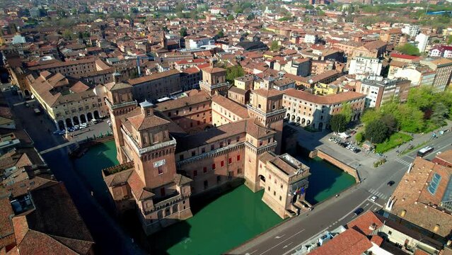 Aerial top down view of Castello Estense medieval castle in Ferrara, Italy. Drone descending with camera down over water moat and brick towers in historic center of Emilia Romagna. Scenic 4k video.