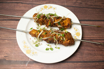 Chicken tikka boti kabab, kebab served in dish isolated on wooden table top view indian spices food