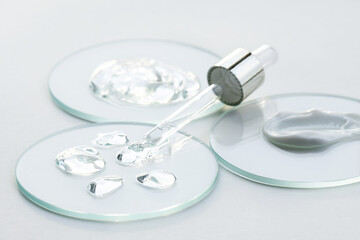 Glass petri dishes and glass pipette various cosmetic products cream gel, medical research. Cosmetic white background.