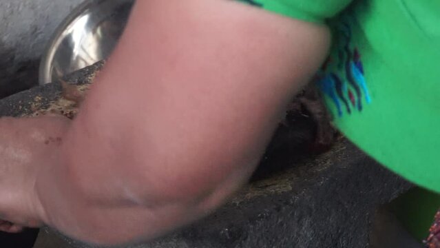 Grinding chili peppers with metate
