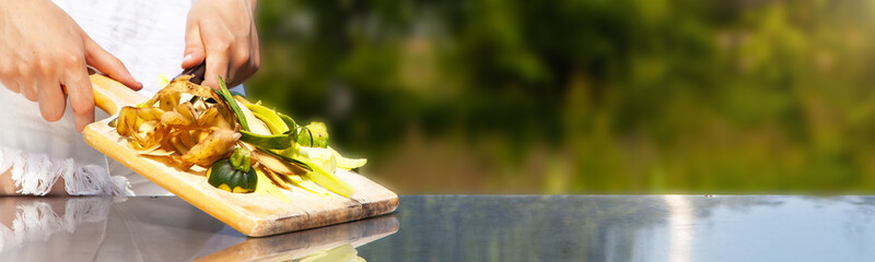 Young housewife holding a cutting board with vegetable peel, cooking waste, on a kitchen worktop,...
