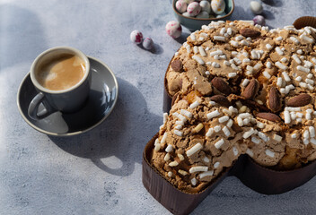 Colomba pastries, a cup of espresso coffee and chocolate colored quail eggs on a stone table. Italian traditional food with hard shadows.