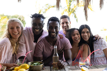 Portrait of happy diverse friends embracing and smiling at beach, with copy space
