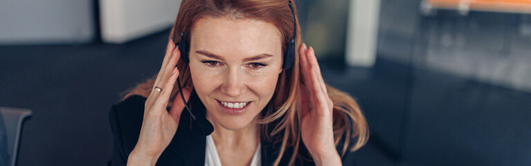 Business Woman in headphones talking online with client during working day in office