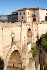 Ronda, Andalusia, Spain - March 15, 2023: The famous bridge with arched vaults between the rocks of the gorge on a sunny day. Landmark of the city.