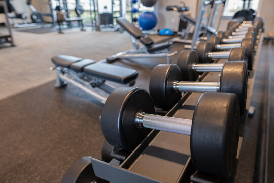 Dumbbells on weight rack with workout room out of focus in the background