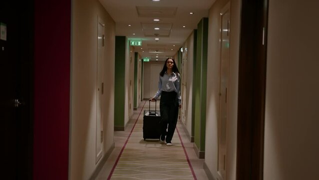 A girl with a suitcase walks down the corridor of a hotel  businesswoman on trip the concept of travel