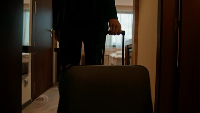A man with a suitcase enters a hotel room after a flight during a trip recreation concept
