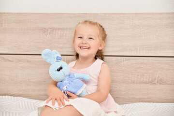 Girl at home with a plush bunny in her hands