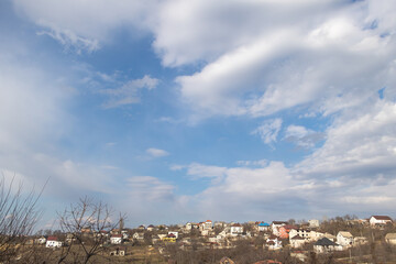 Village in the spring on a background of blue sky with clouds